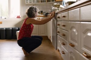Flasche mit Reiniger neben geöffneter Spülmaschine
