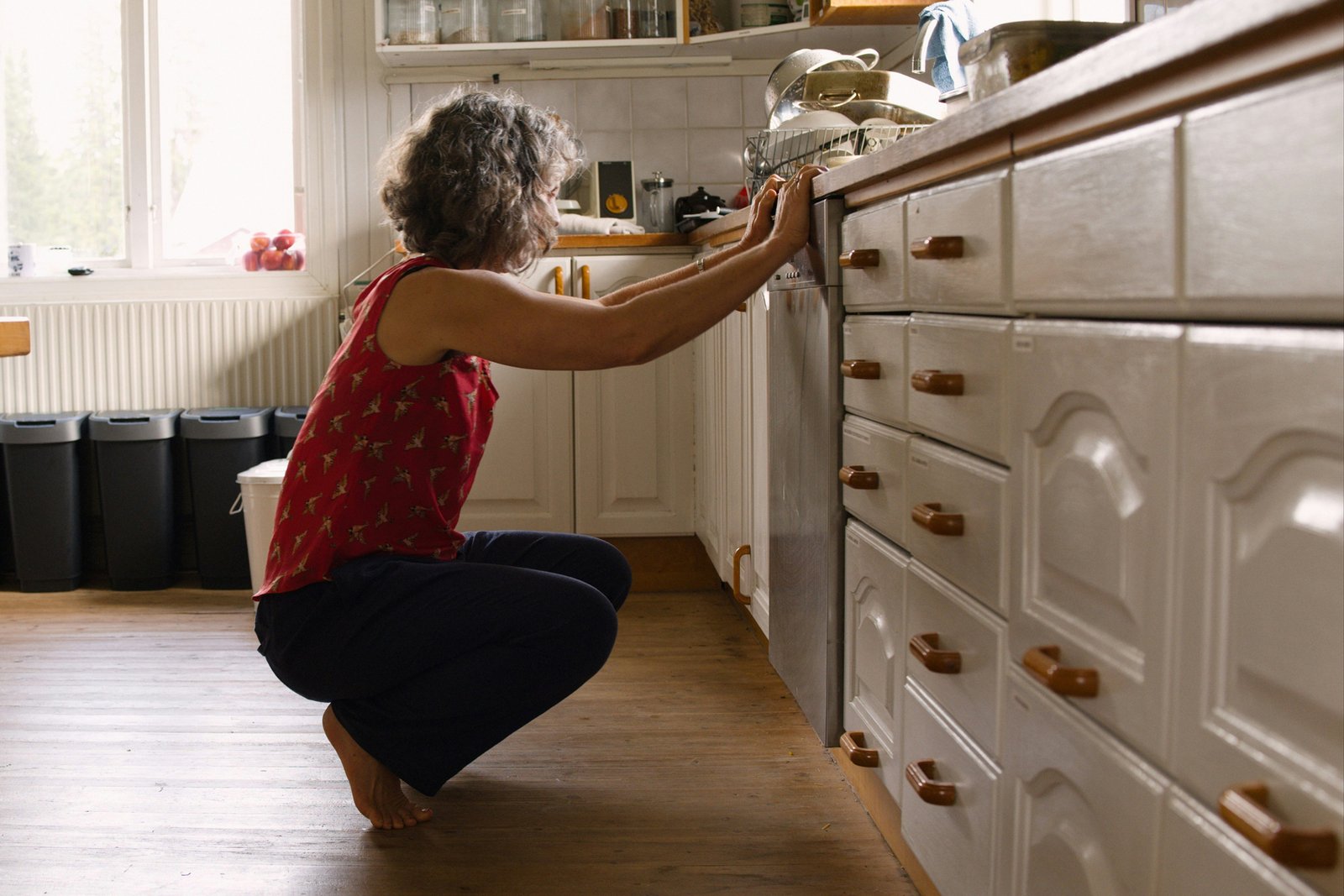 Flasche mit Reiniger neben geöffneter Spülmaschine
